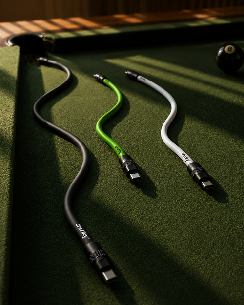 Three curved USB-C cables in black, green, and white, branded with 'cloudy', are laid out on a green felt pool table with a 8-ball visible in the background.
